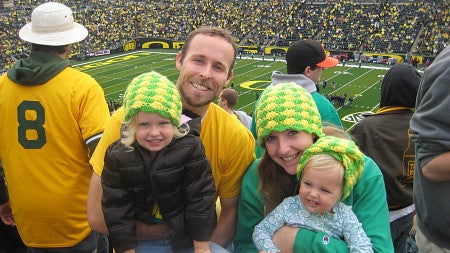 small family posing with football field in background