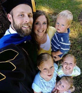 man in college graduation robe with family